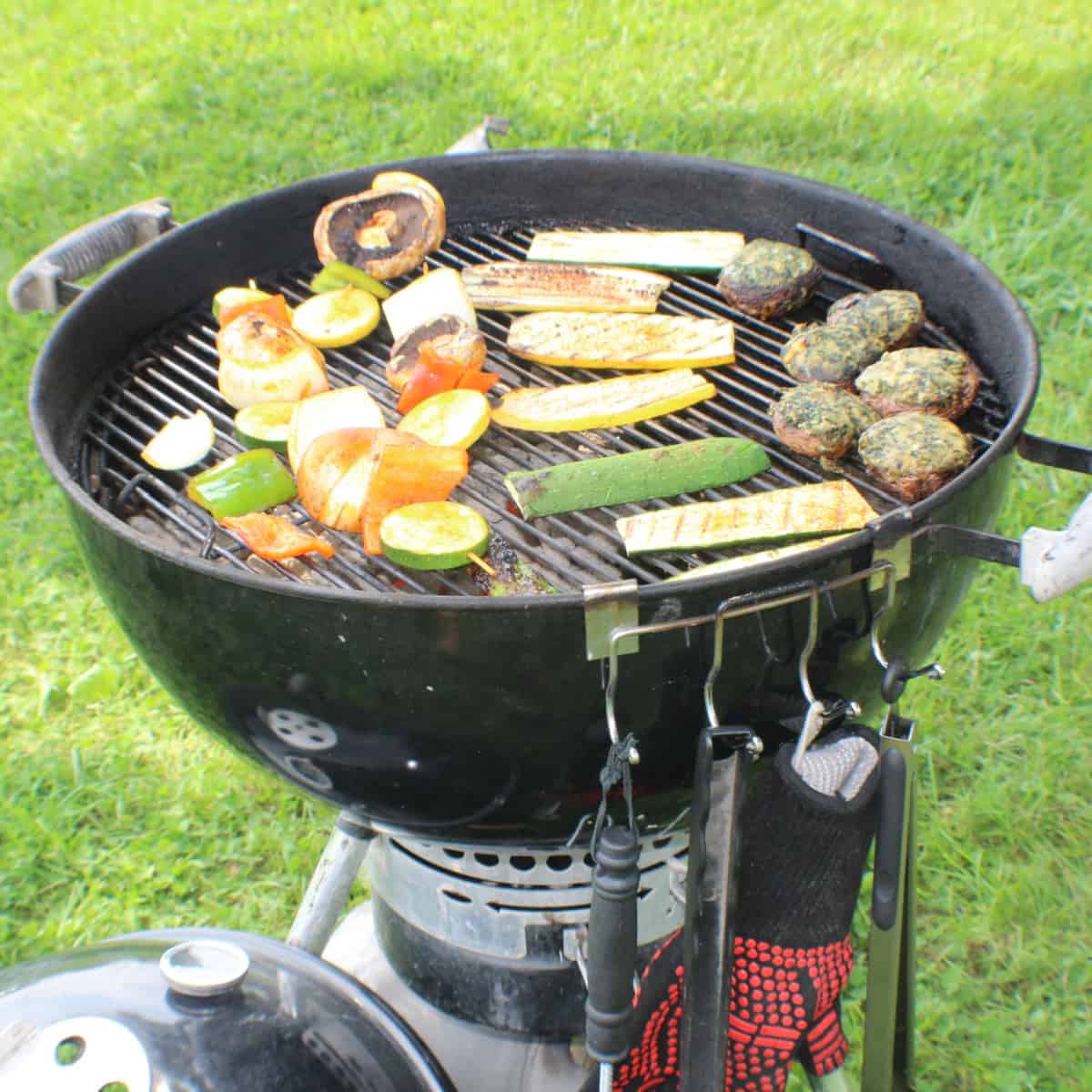 weber charcoal grill cooking meat and veggies
