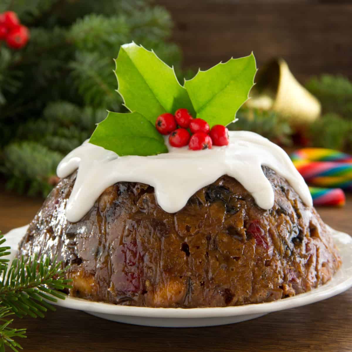 Christmas pudding on white plate topped with leaves