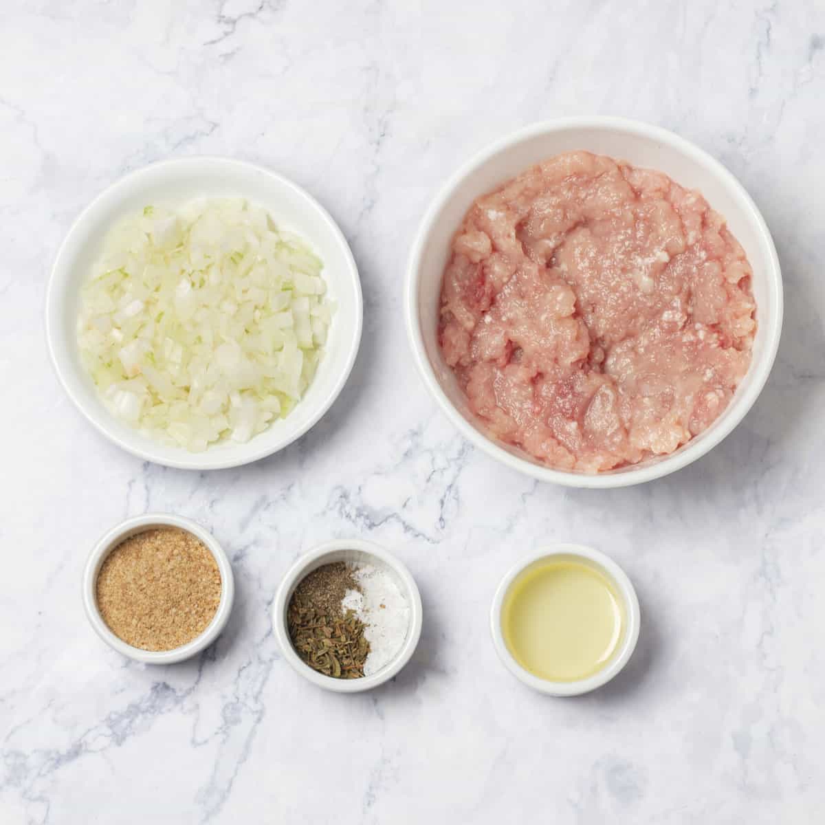 Raw ingredients of ground turkey, chopped onion, and spices in separate dishes.