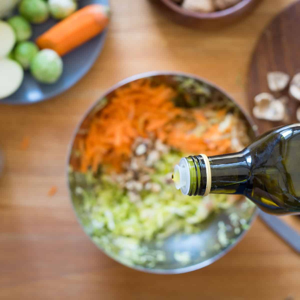 olive oil pouring onto vegetables in bowl