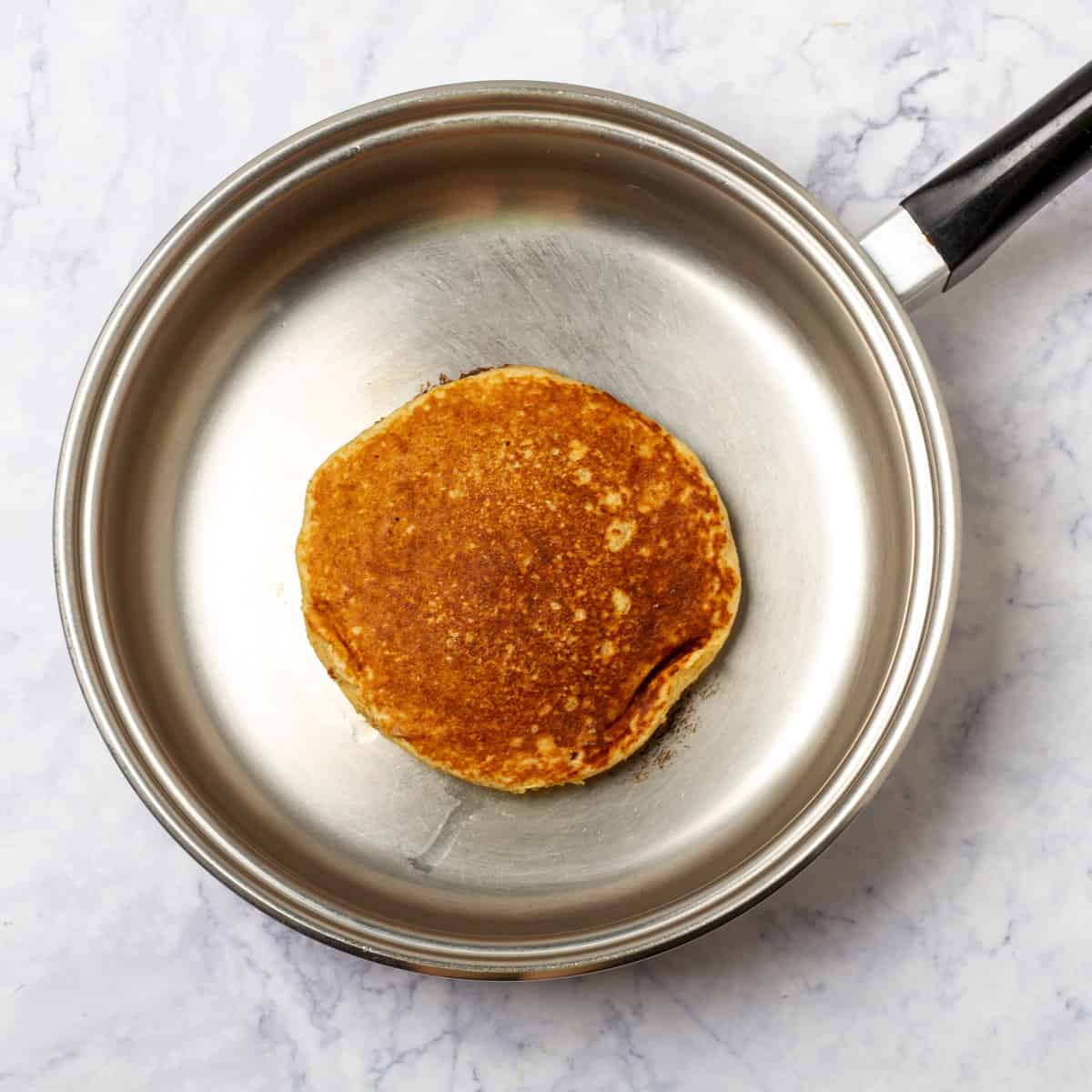 An apple pancake cooking in a hot pan.