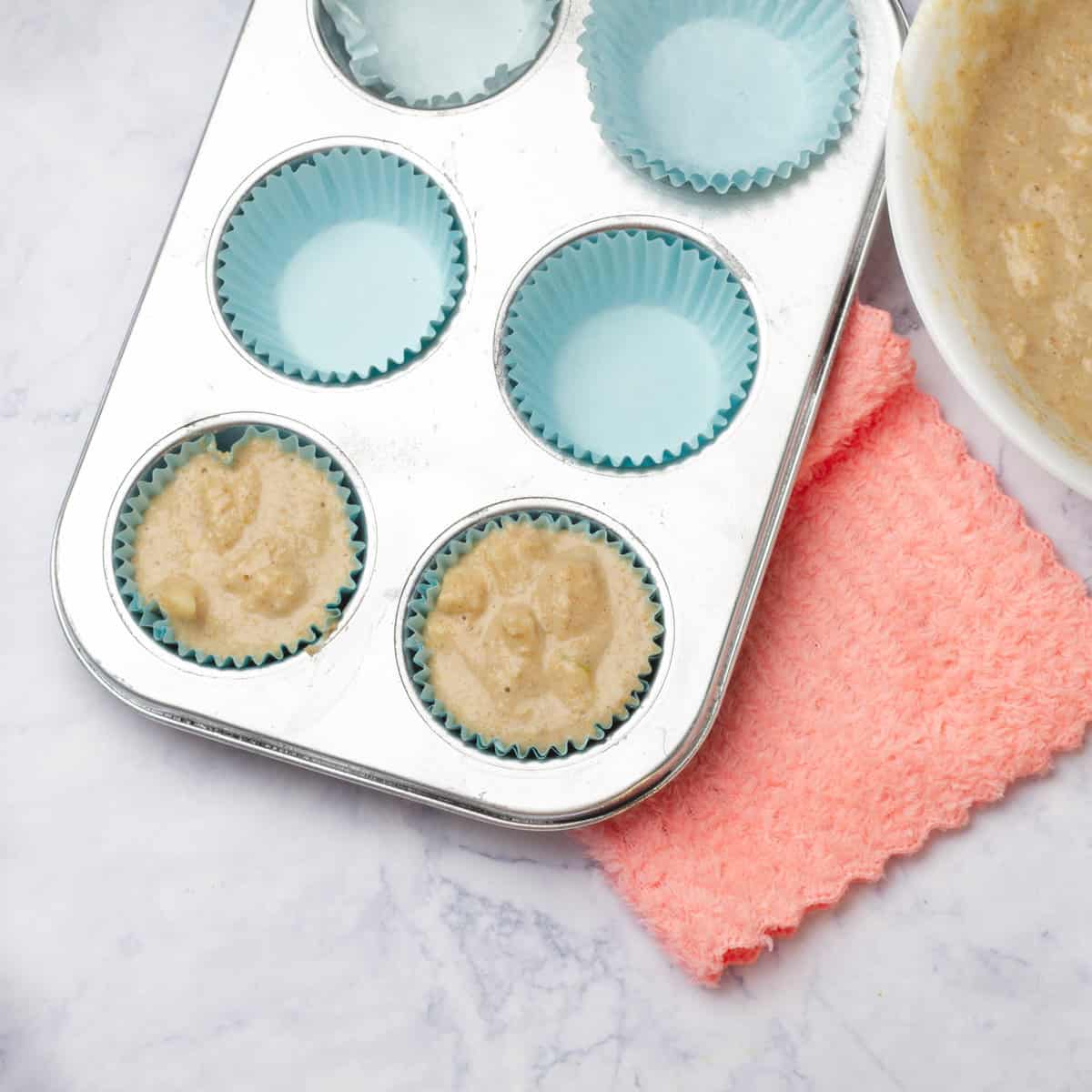 Apple muffin batter in lined muffin tins, ready to bake.