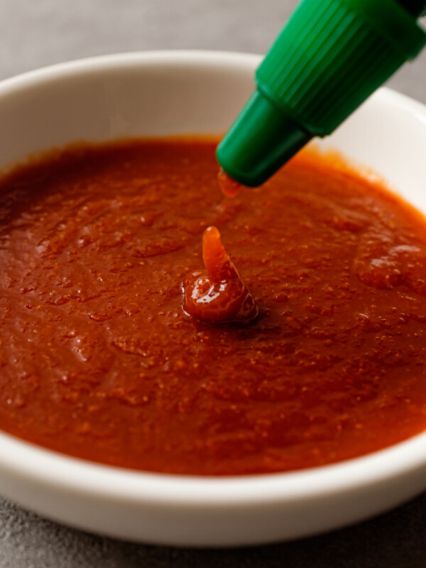sriracha pouring from bottle into white dish