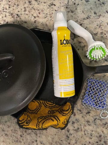 cast iron grill, oil, soap, and brush on a counter