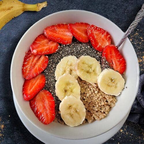A quinoa breakfast bowl on a table with a banana.