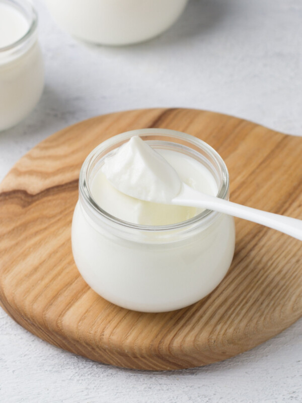 Greek yogurt in jar on wooden cutting board