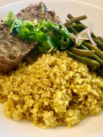Hearty and flavorful Vegan Lentil Loaf on a plate with green beans and quinoa.