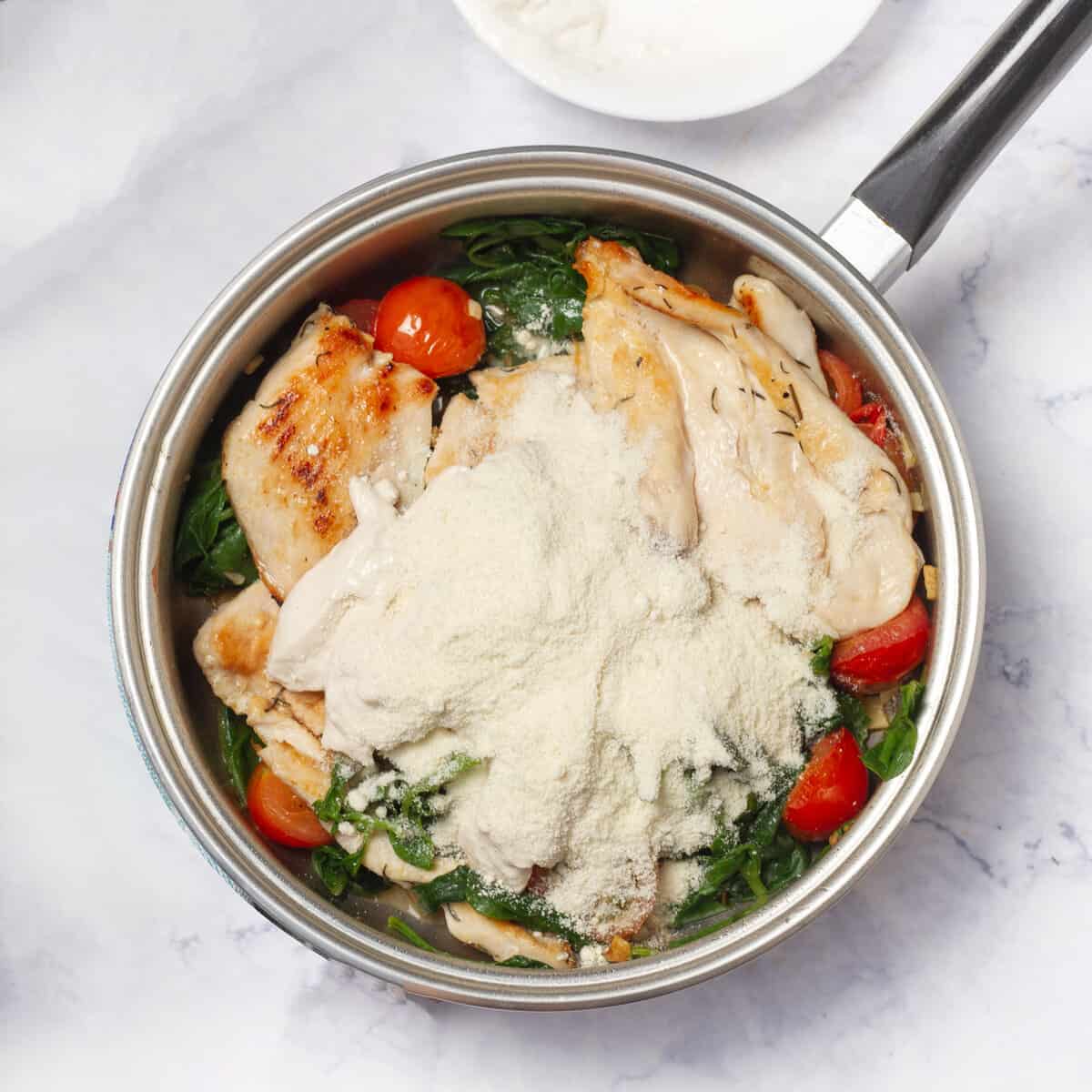 Yogurt and cheese added to the pan of chicken breasts and vegetables.
