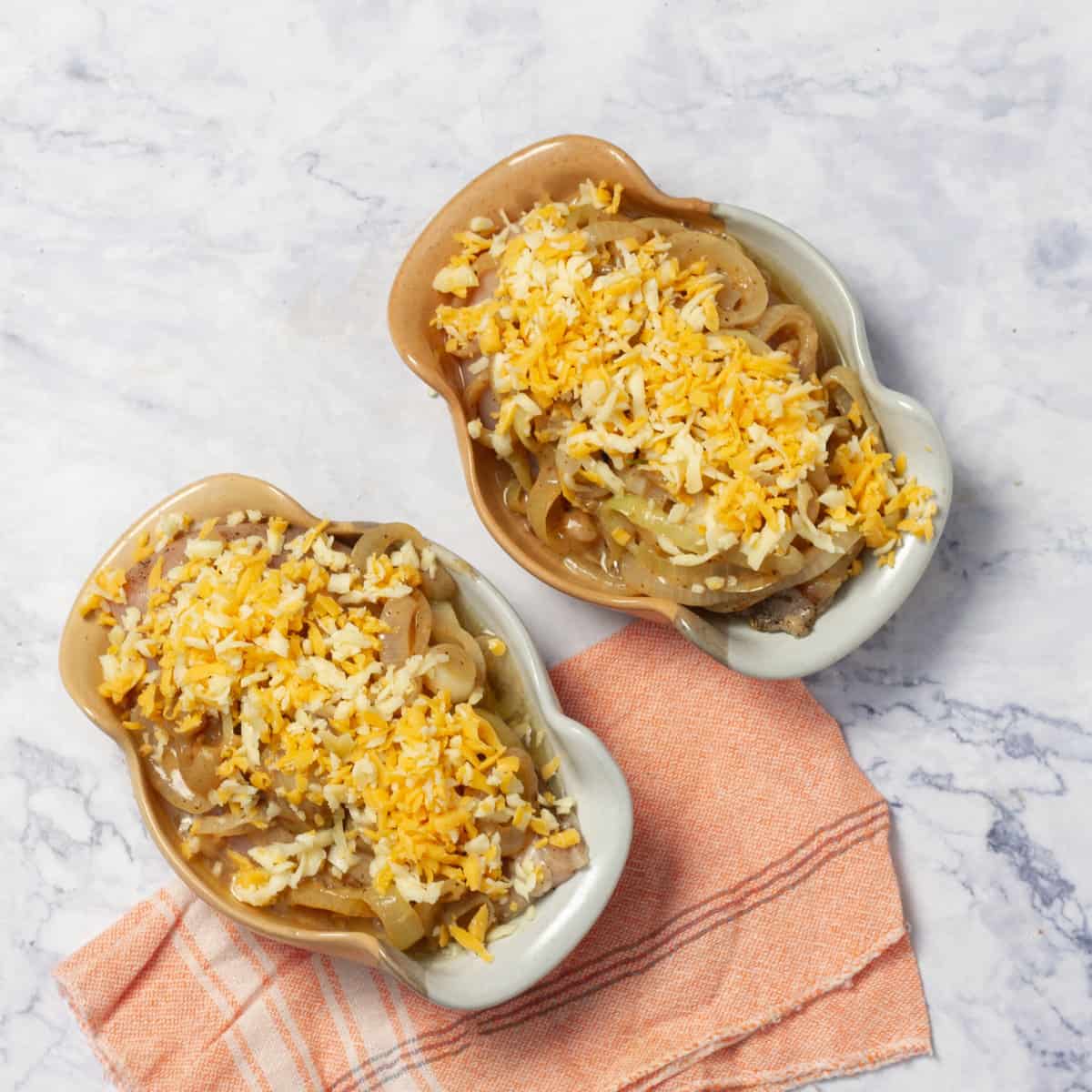 seasoned chicken supremes in a casseroles with the caramelized onions and cheese