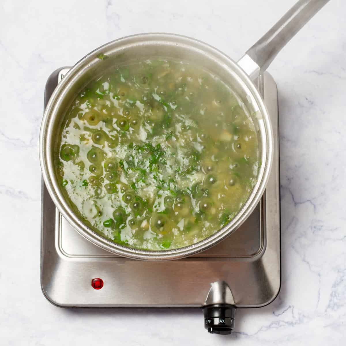 Simmer fish broth, peas, and herbs into a pot 