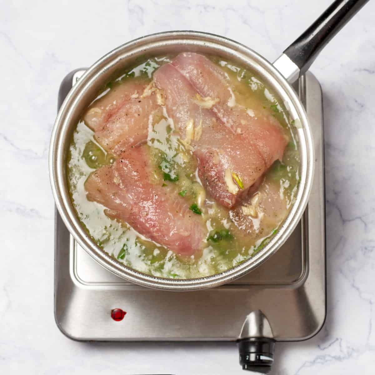 marinated hake fillets cooking into the pot