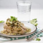 Hake in Green Sauce plated with glass of water