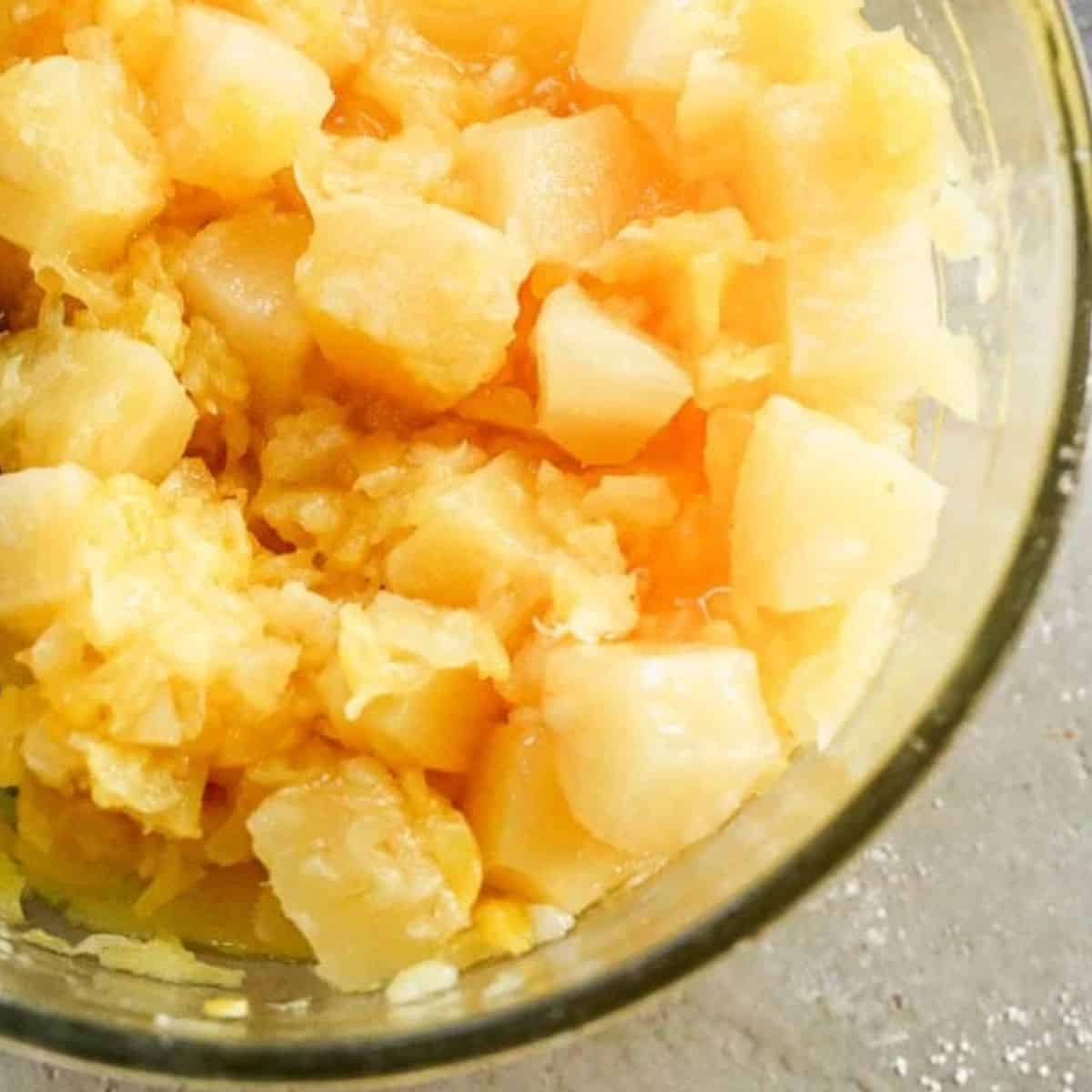 preparing filling for pineapple casserole in clear mixing bowl