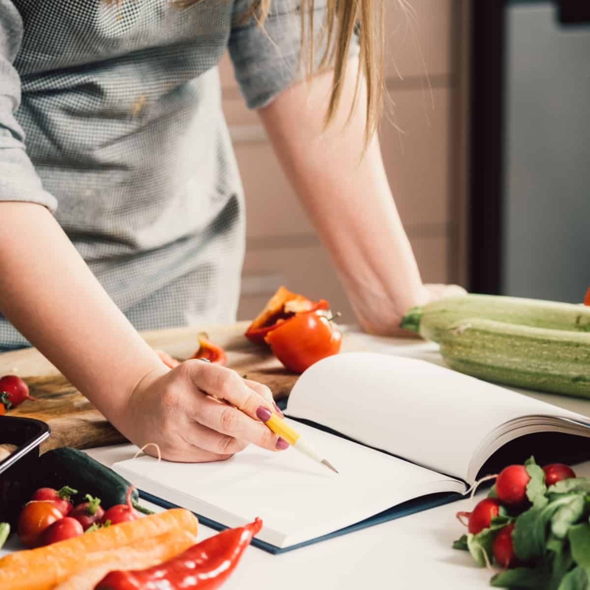 Woman writing in notebook on kitchen counter