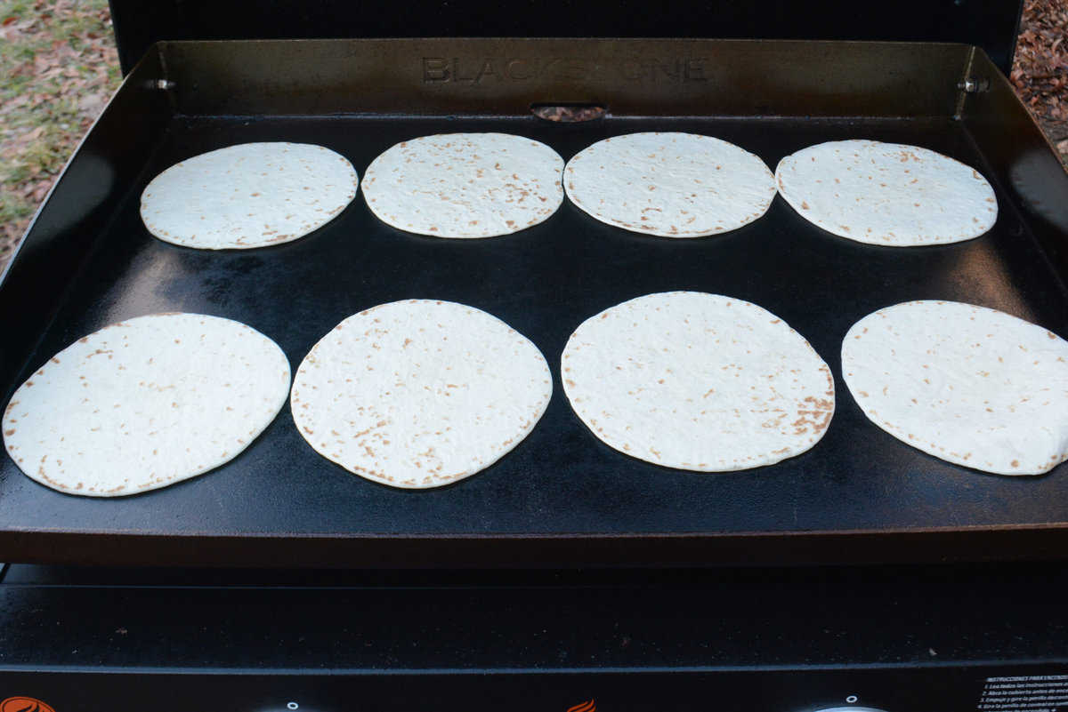 Eight fajita sized tortillas sit on top of the Blackstone 