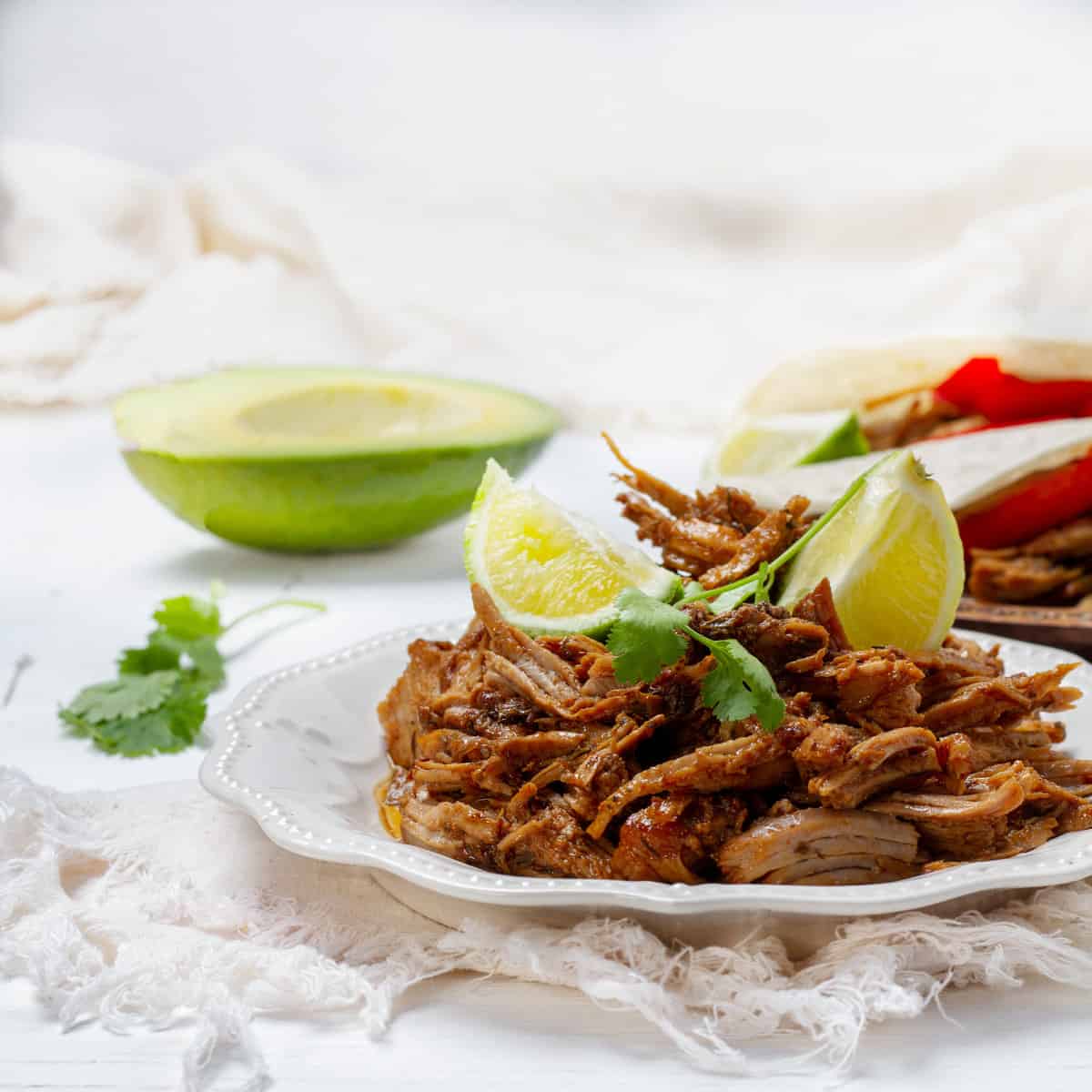 Carnitas platted with lemon slice and avocados