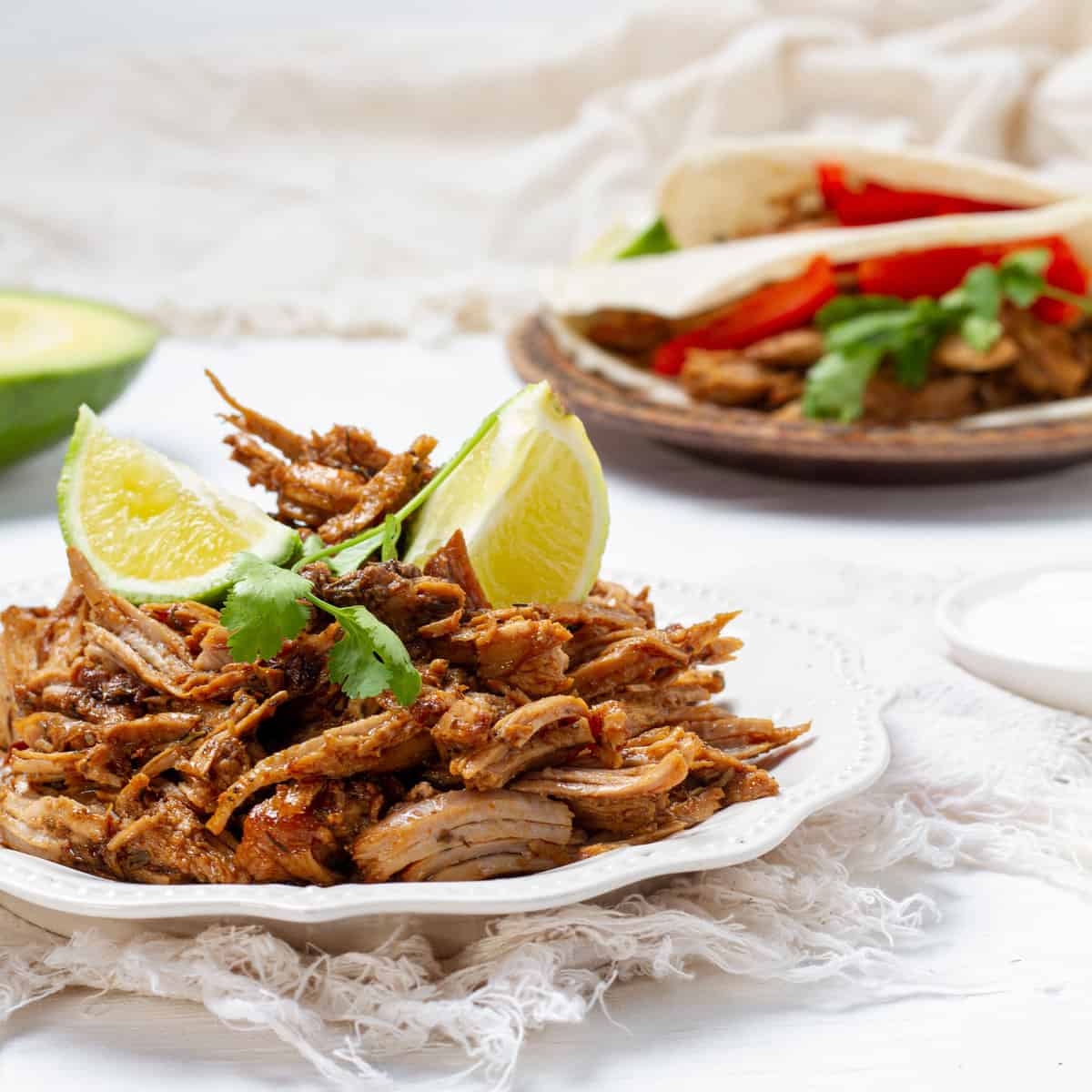 Carnitas platted with lemon slice and avocados
