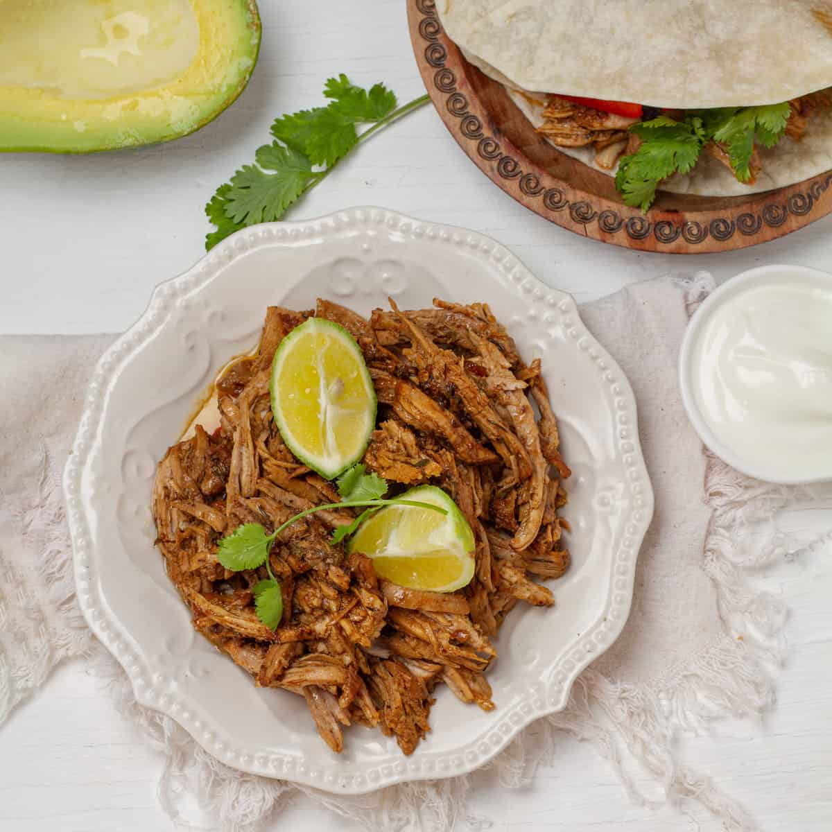 Carnitas platted with lemon slice and avocados