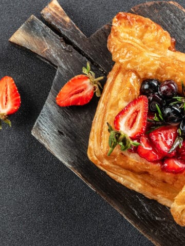 french puff pastry with blueberries and strawberries sitting on dark plate