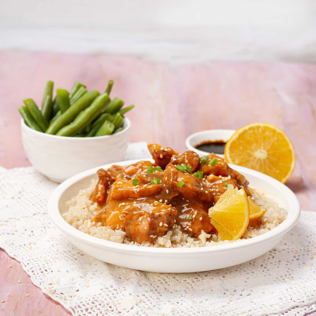 Orange Chicken served with lemon and bowl of beans