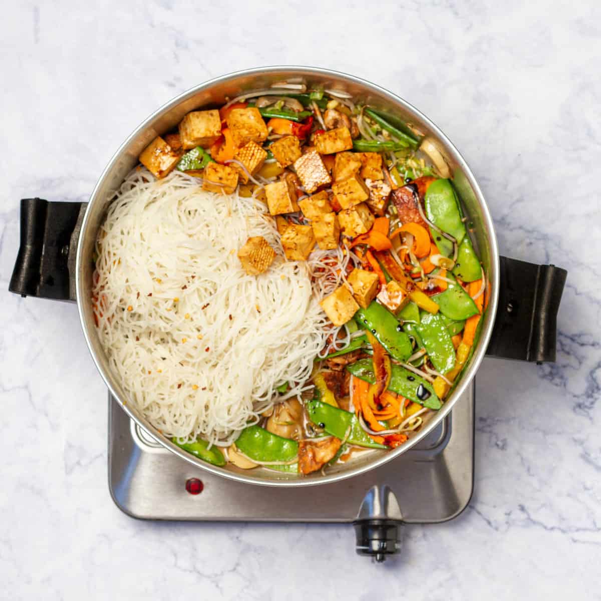 Combine vegetables with tofu, chicken and rice noodles in a skillet