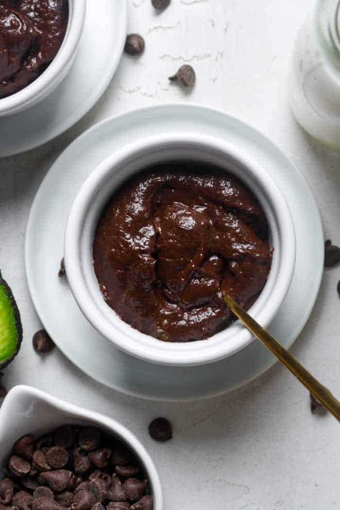 Avocado chocolate pudding in a bowl with spoon in it on a table.