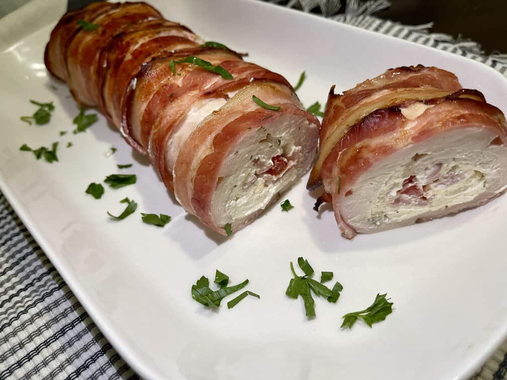 A bacon chicken roll on a white platter.