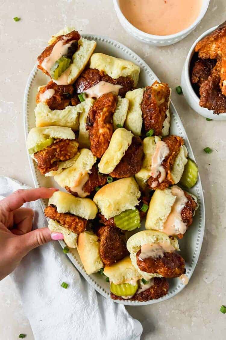 A hand reaching out for a Bang Bang chicken mini on a platter.