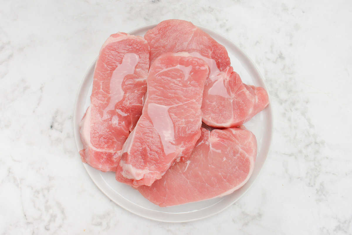 raw pork chops drizzled with olive oil