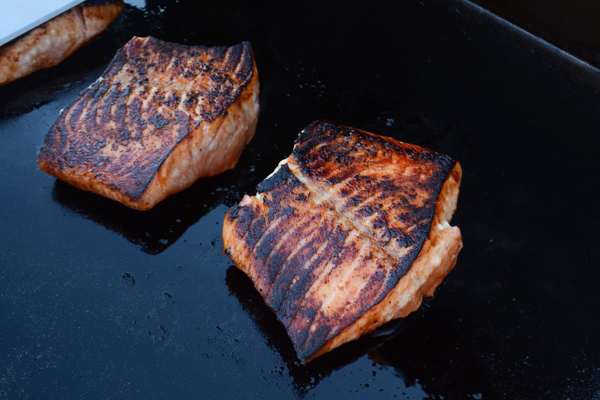 flipped salmon filets set on the blackstone griddle, showing the sear, texture and caramelization of the marinade.