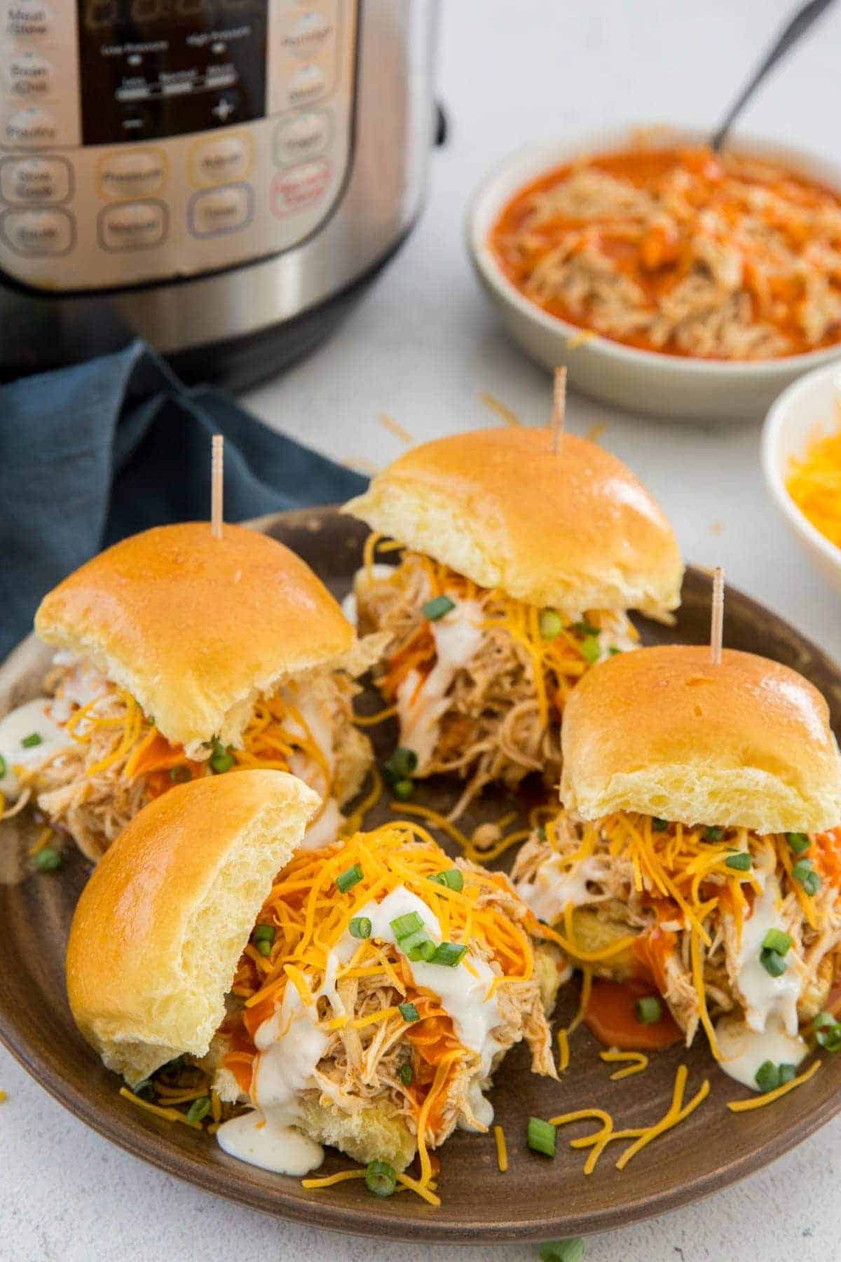 Buffalo chicken sliders on a tray with an Instant on a table.