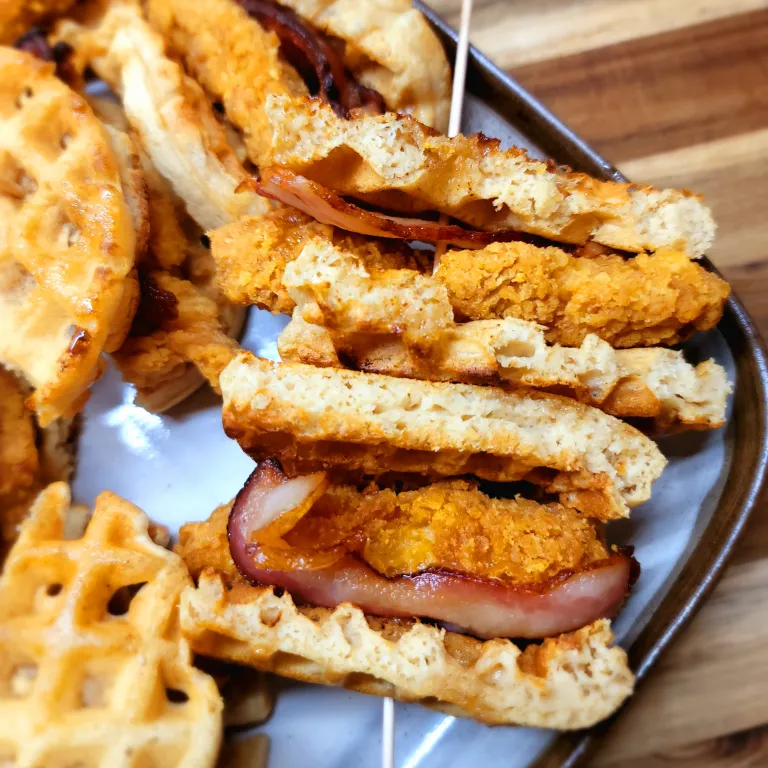 Chicken and waffle sliders on a tray a table.