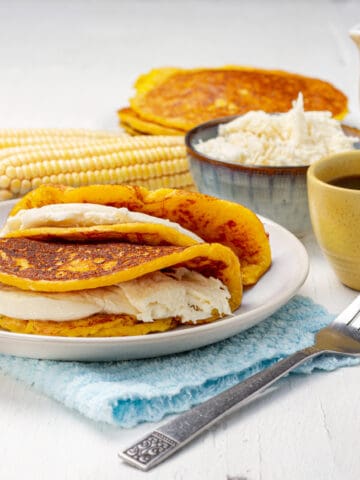 Cachapas platted with a cup of coffee and corn