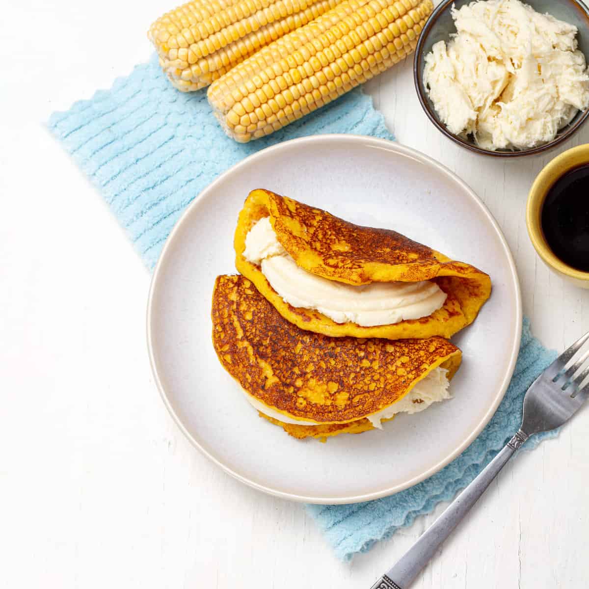 Cachapas platted with a cup of coffee and corn