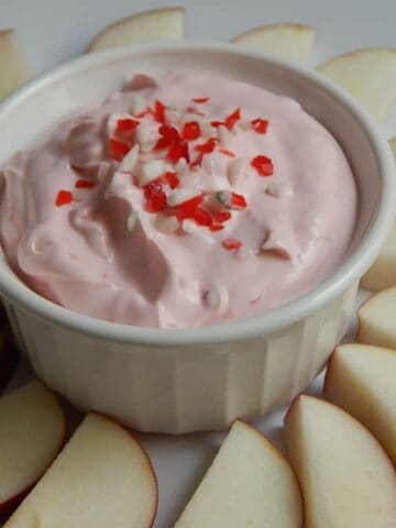 Candy cane fruit dip in a ra.mekin surrounded by fruit