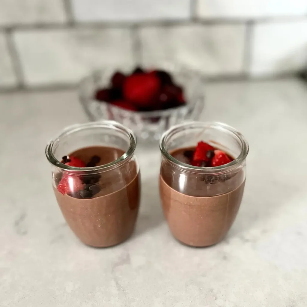 Dark chocolate pudding in glass jars on a counter.