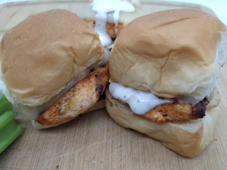 Grilled chicken sliders on a wooden cutting board.
