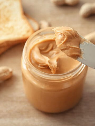Peanut butter scooped out of a jar with a knive