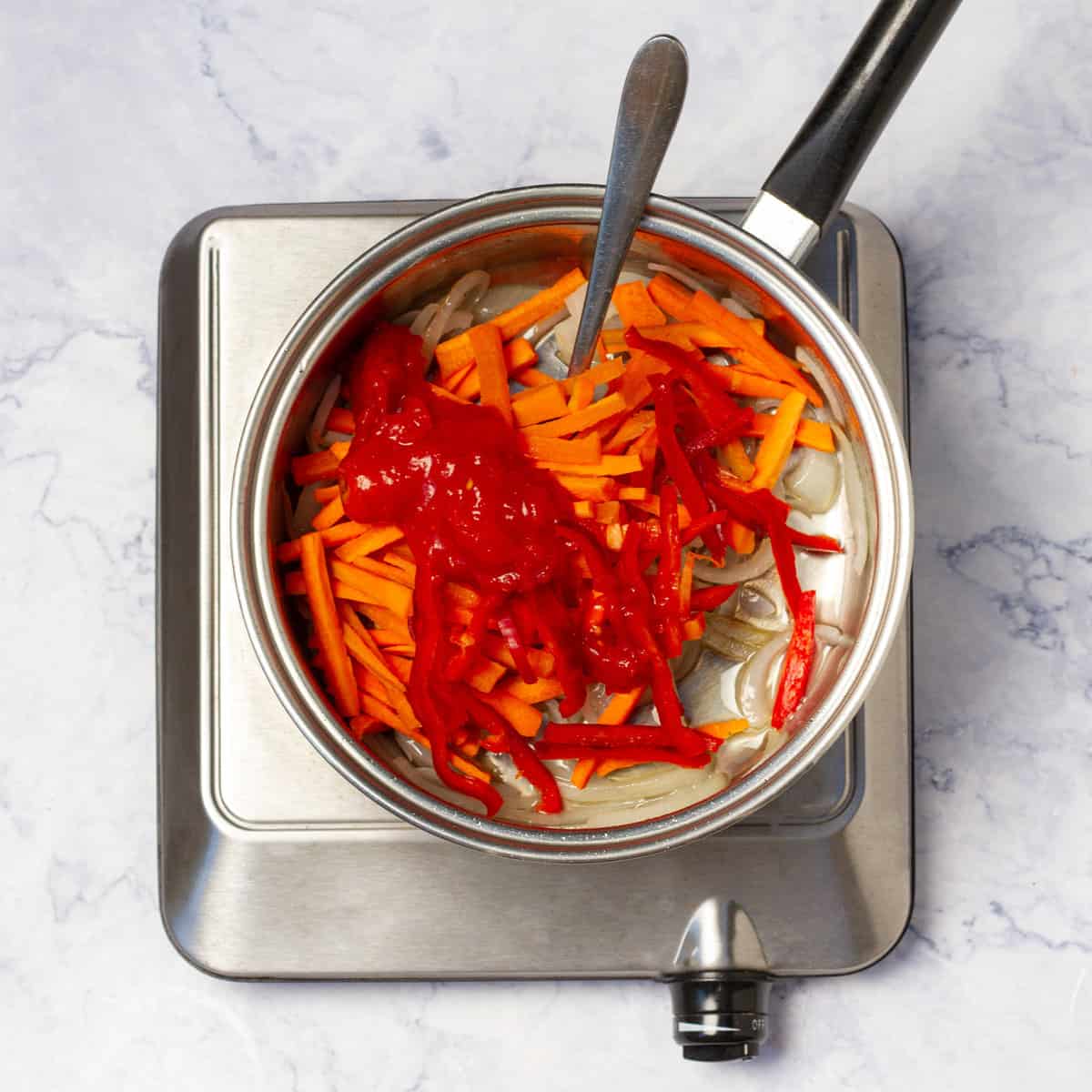 Cooking sliced onion, red bell pepper, and carrot