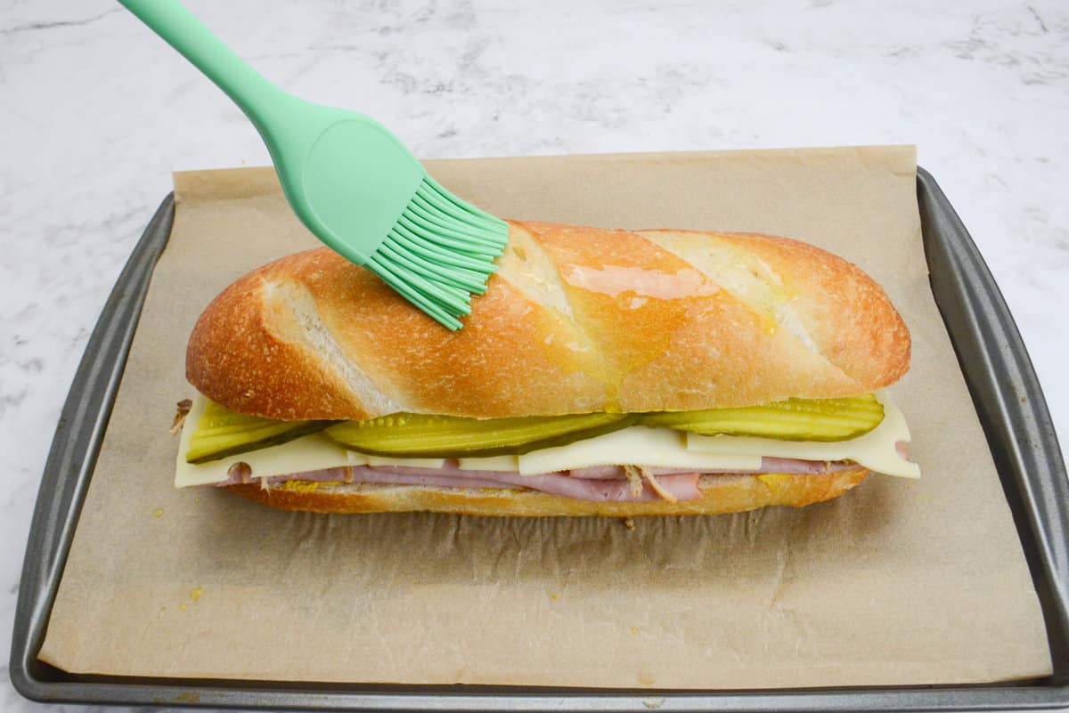 Closed Blackstone Cuban Sandwich with olive oil being brushed on top. 