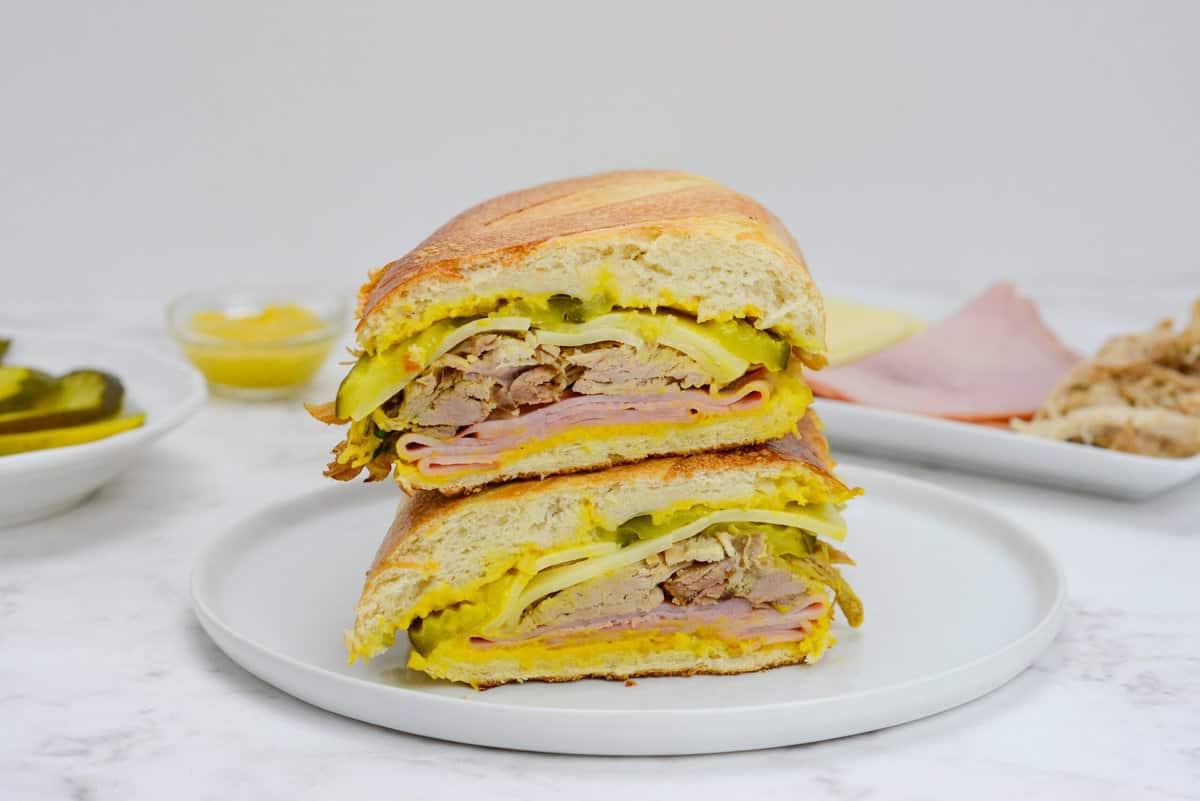 Two halves of Blackstone Cuban Sandwich stacked on top of each other on a white plate.