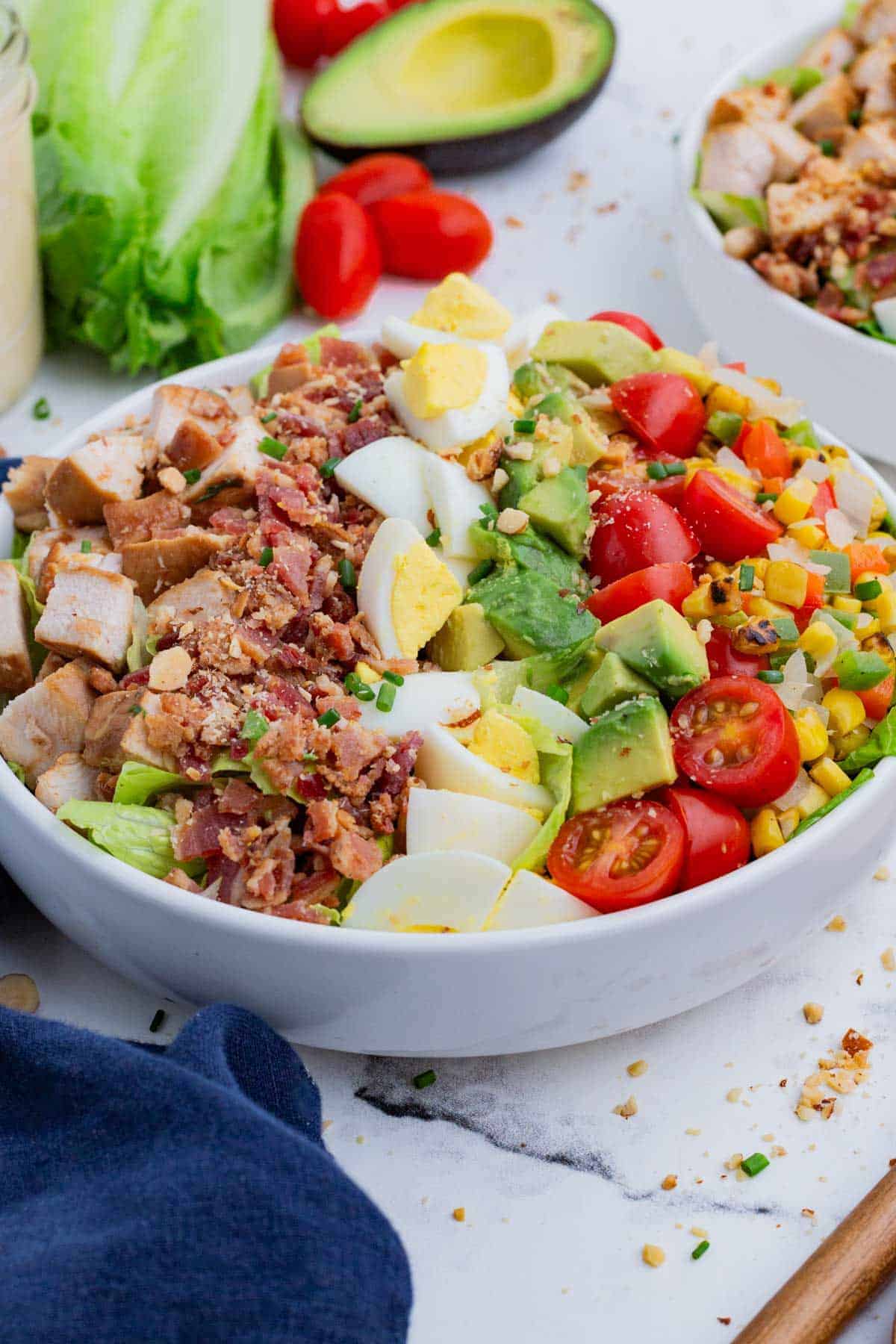A Chicken Cobb Salad in a white bowl on a table.