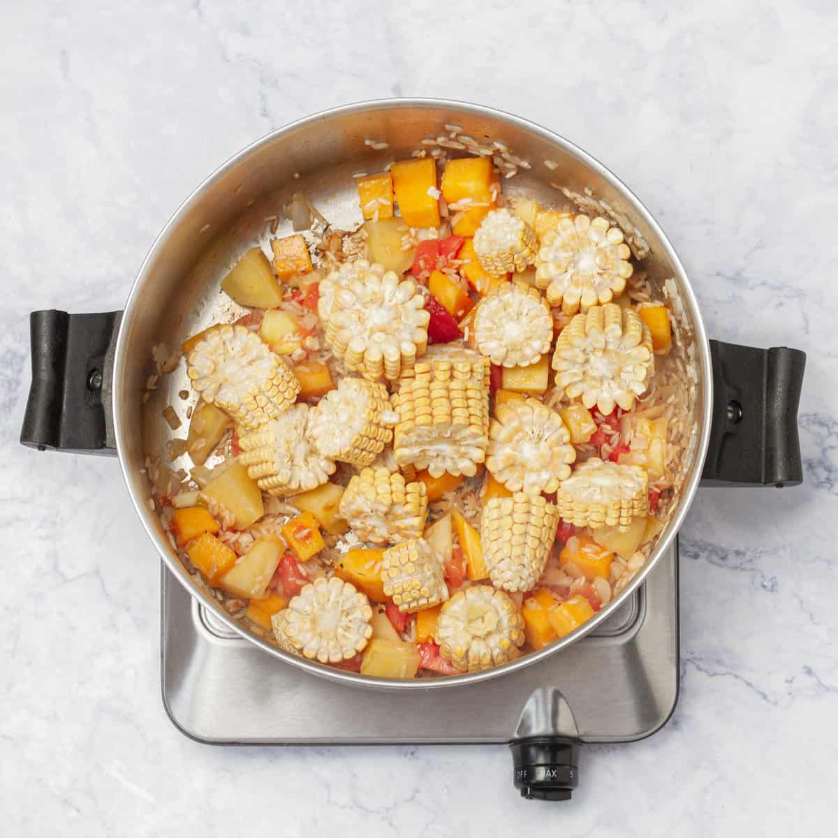 Add corn to cooked vegetables