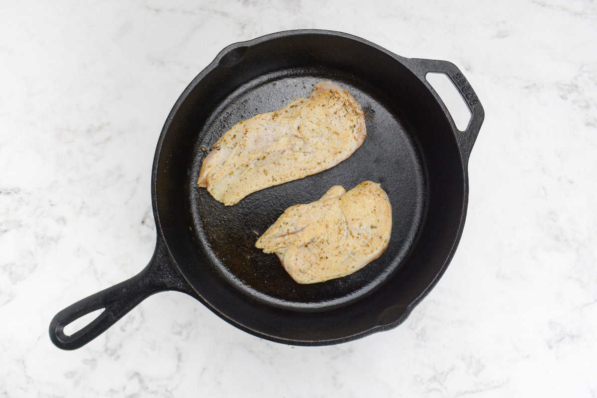 A cast iron skillet with seared chicken 