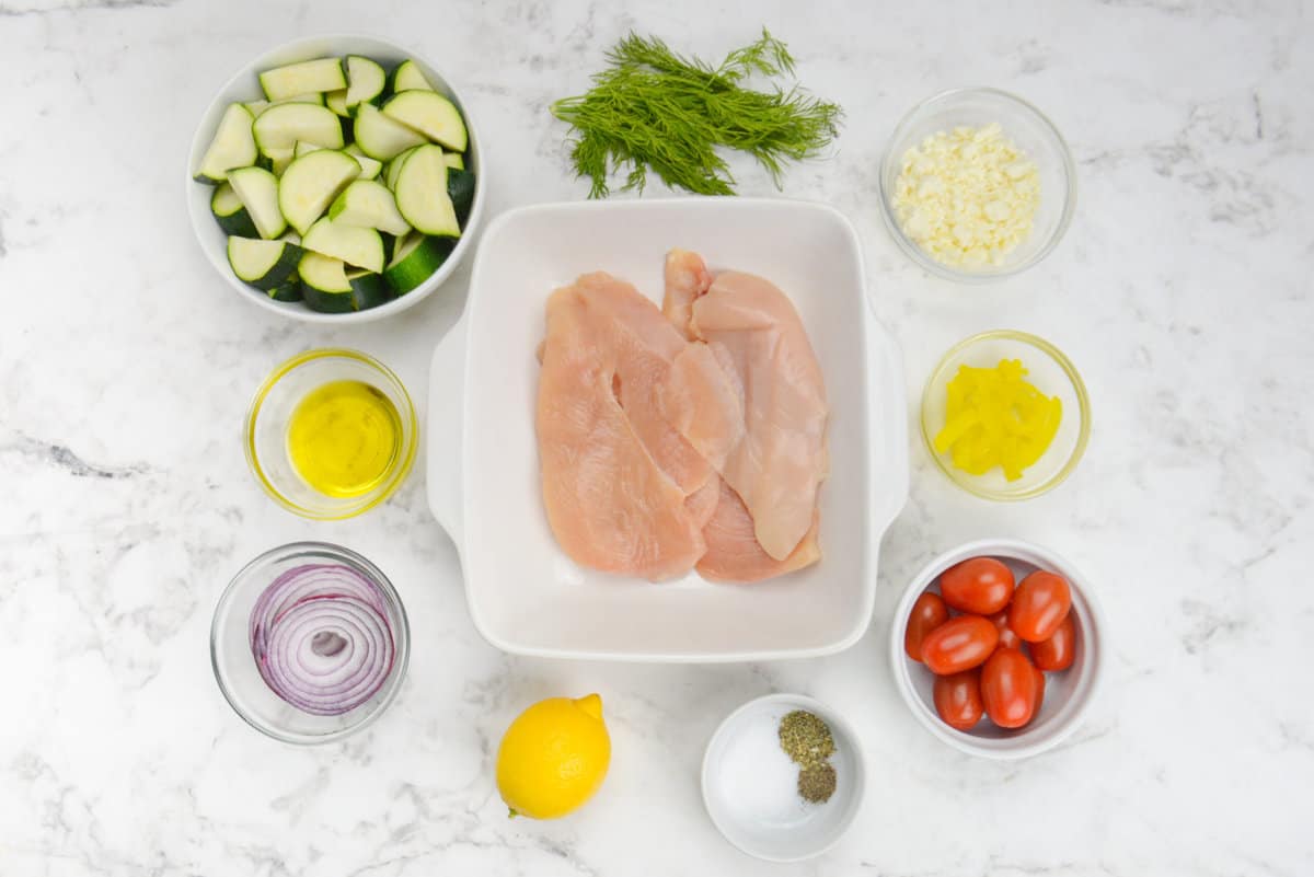 The ingredients to make Greek sheet pan chicken are placed in various size bowls