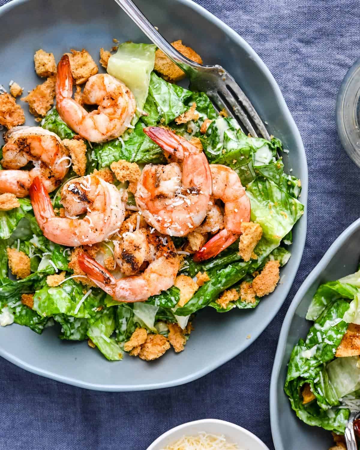 A Grilled Shrimp Caesar Salad in a blue bowl with a fork in it.