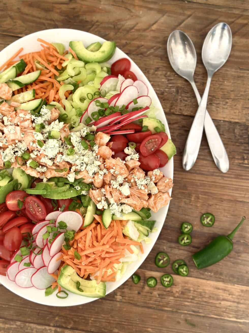 A Healthy Buffalo Chicken Dinner Salad on a serving platter on a wooden table.