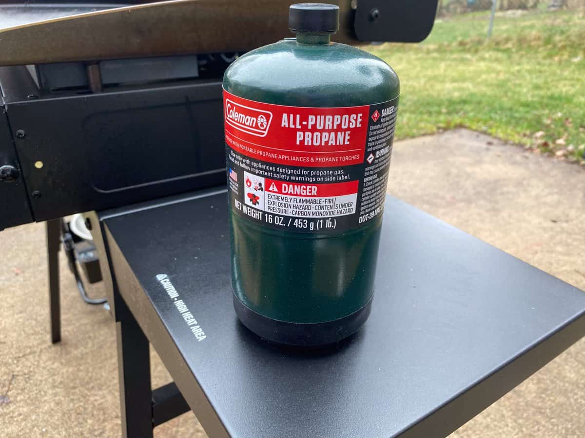 A green can of propane sits next to the Blackstone 