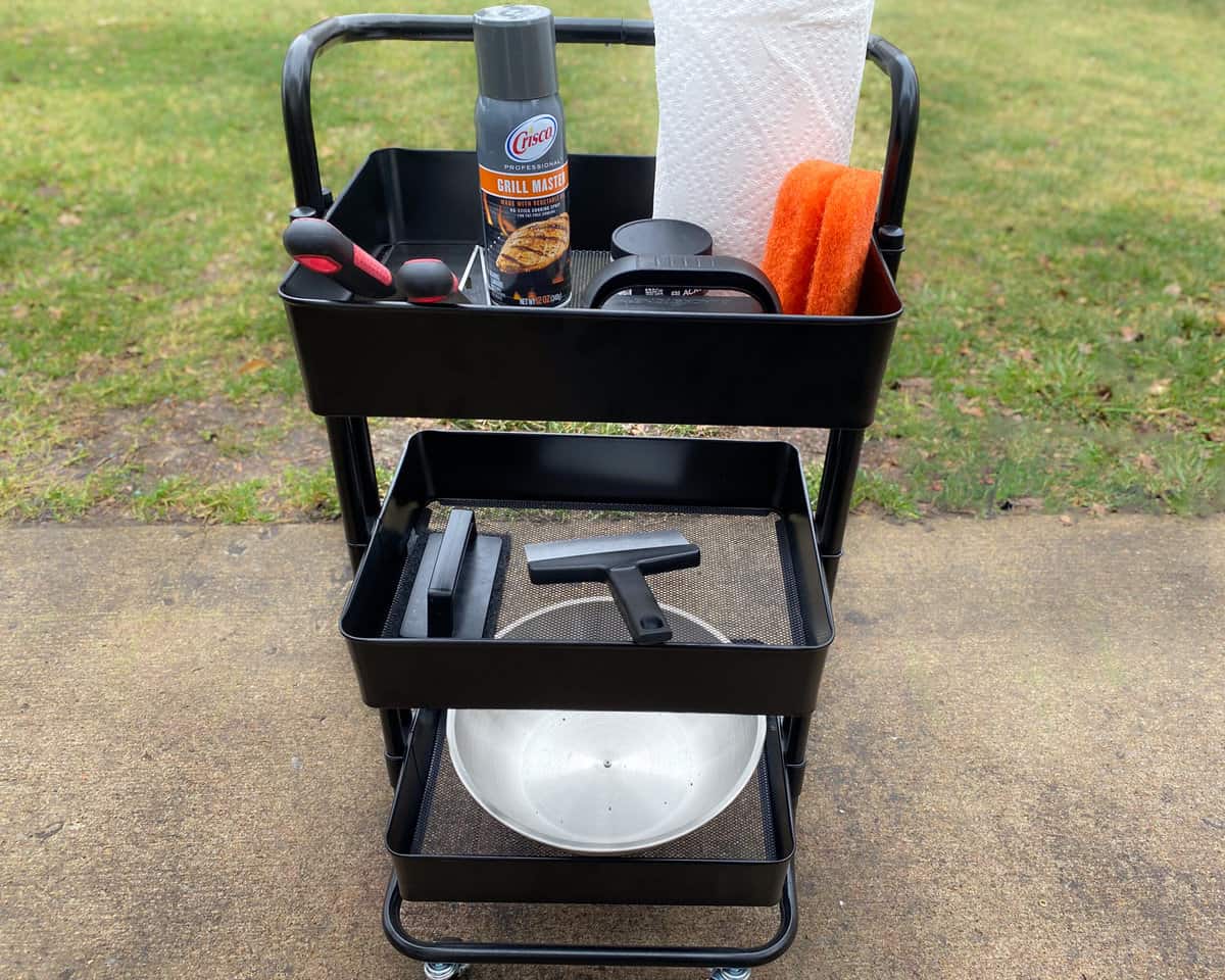 Small three-tiered cart filled with Blackstone cleaning and cooking accessories sits on patio