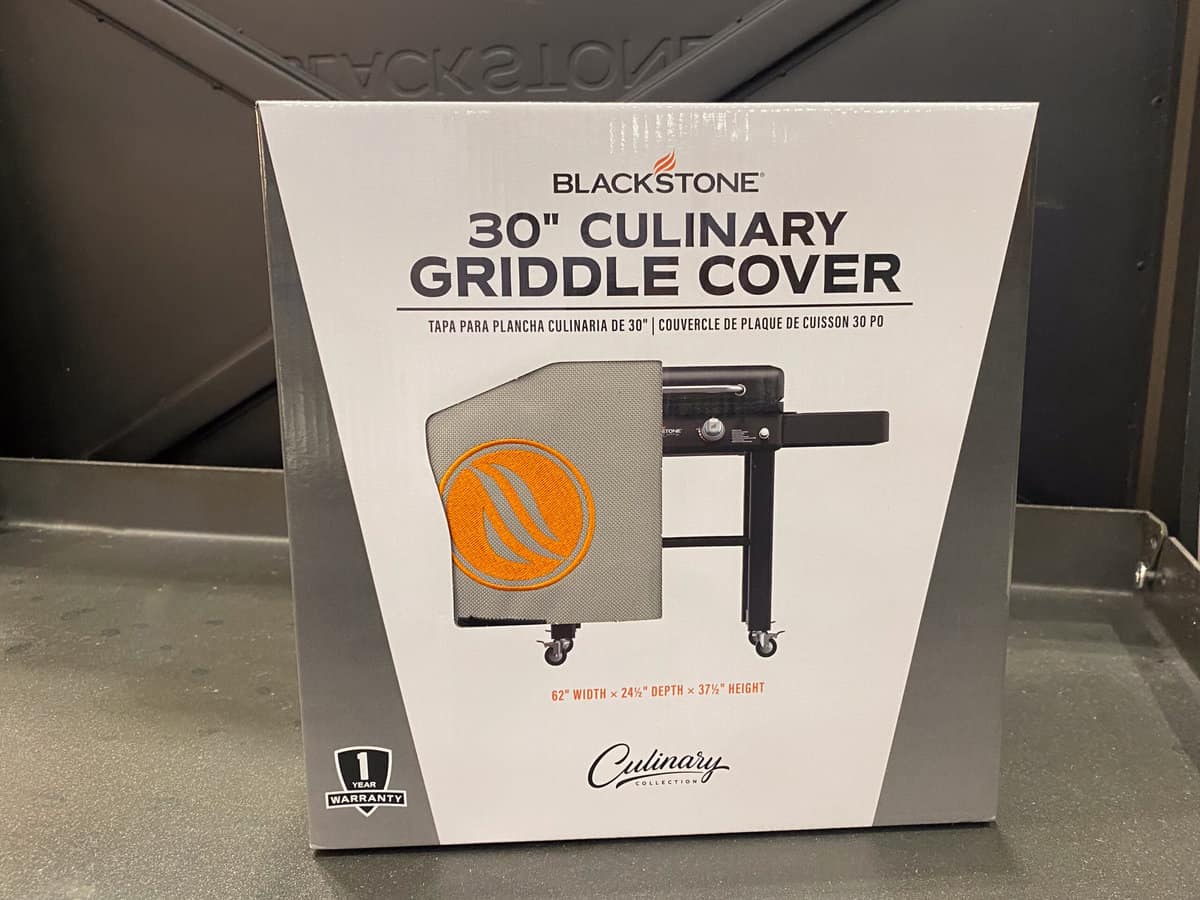 Unopened box containing Blackstone griddle cover is placed on griddle surface 